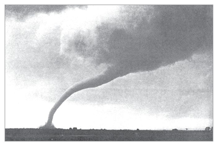 Photograph of a tornado funnel reaching the ground beneath a dark cloud.