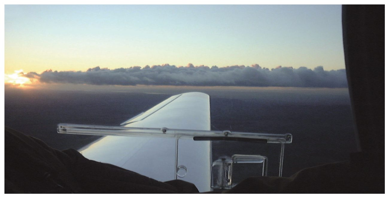 A layer of stratiform cloud on the horizon seen from an aircraft, with the tailplane in view.